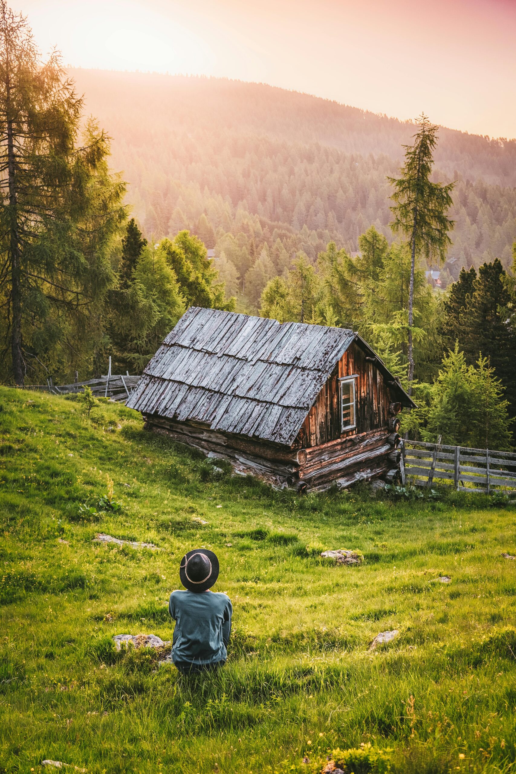 A serene landscape featuring a wooden cabin, lush forest, and vibrant sunset.